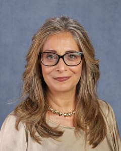 Woman with glasses and long, wavy hair.